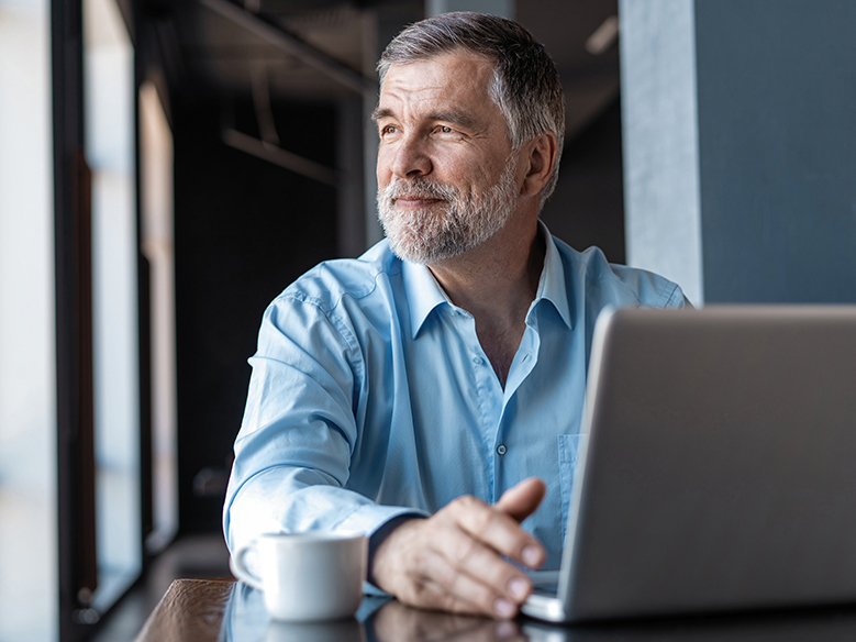 Man on a computer having a cup of coffee.